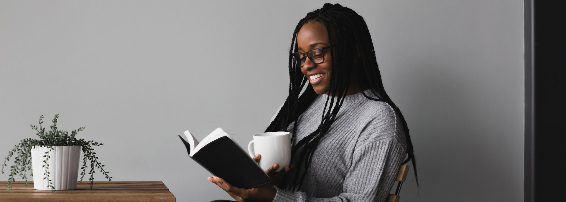 Woman smiling with coffee and book in hand