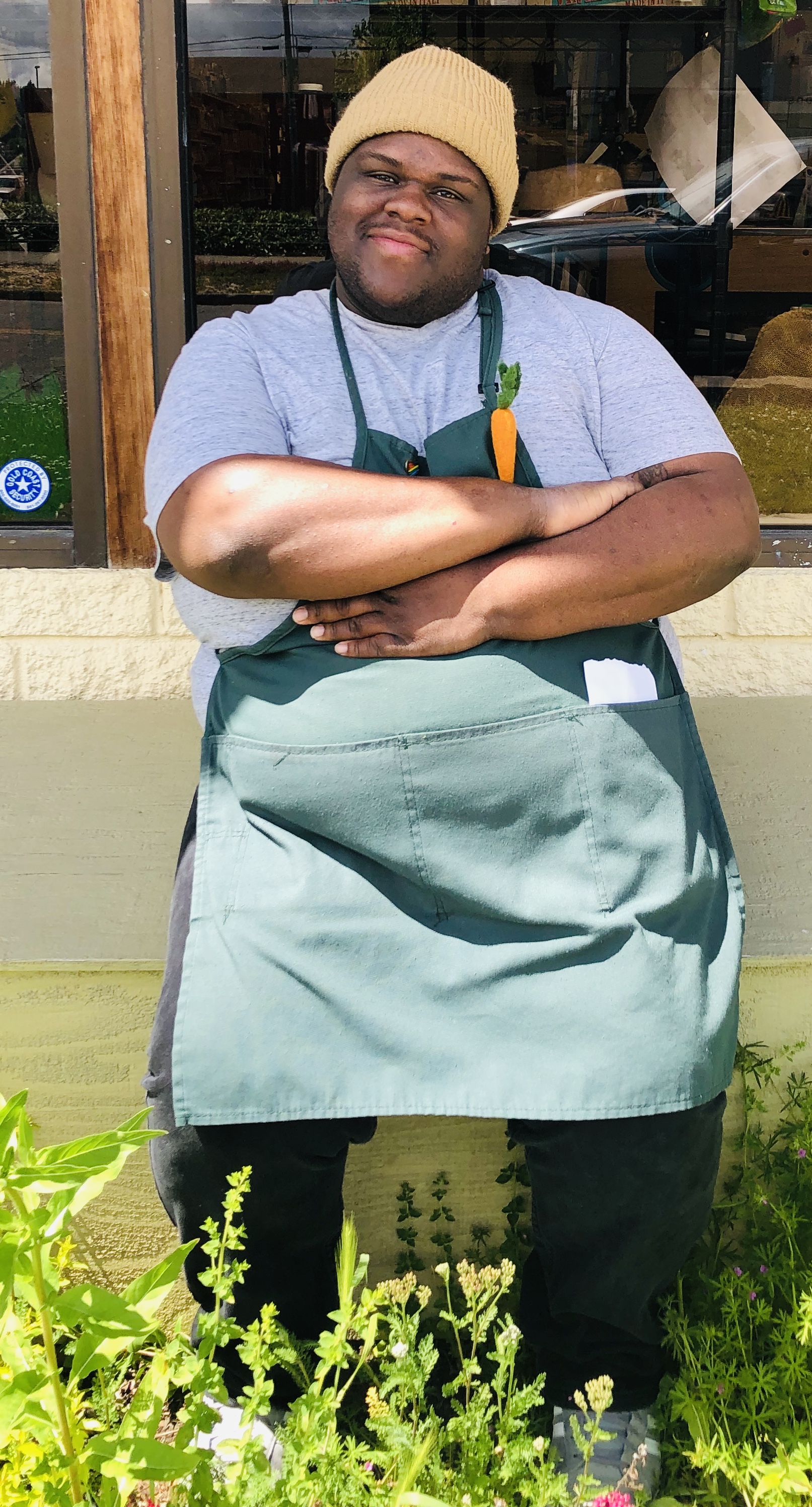 Pic of Jamr in front of Co-op wearing apron, arms crossed