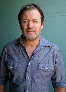 Pic of Willy from waist up: blue shirt w/white buttons, green background