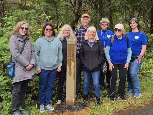 Members of Sole mates standing next to trail marker they sponsored at Topits Park