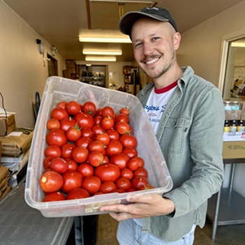 Pic of tim holding bin full of toamtoes in the Co-op