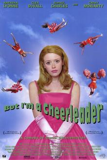 A blue sky with clouds as the background, a teen girl with red hair stands in the center of the page, wearing a pink dress. There are five cheerleaders in the sky surrounding the cenetreal figure. 