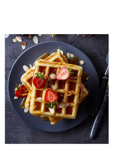 3 stacked waffles with syrup and four strawberries