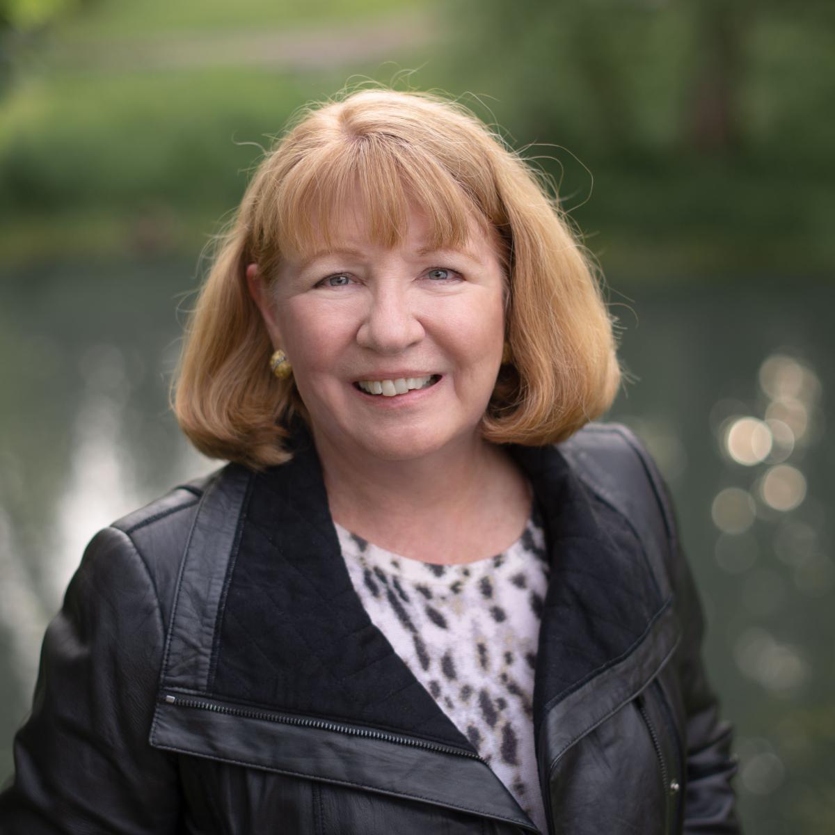 Author Photo of Kay from chest up, wearing black jacket