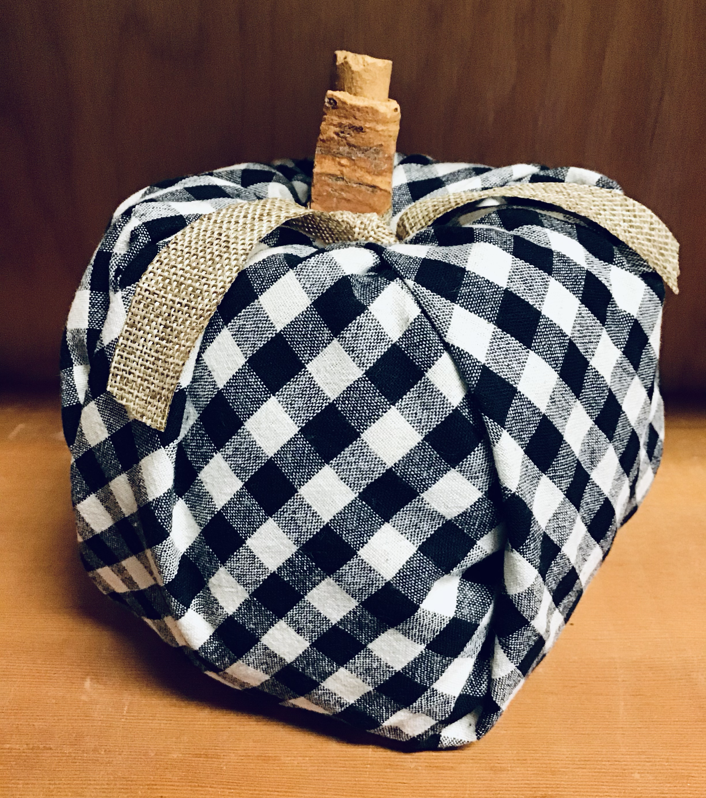 Black and white gingham fabric pumpkin with cinnamon stick stem that has burlap ribbon tied to it.